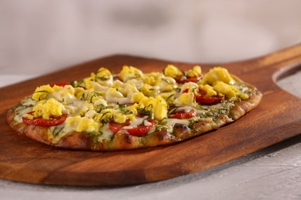 Breakfast pizza topped with eggs, cheese, and breakfast sausage