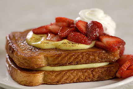 Crème brûlée stuffed French toast topped with berries and powdered sugar