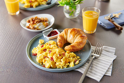 Plated breakfast featuring scrambled eggs, potatoes, and breakfast meats